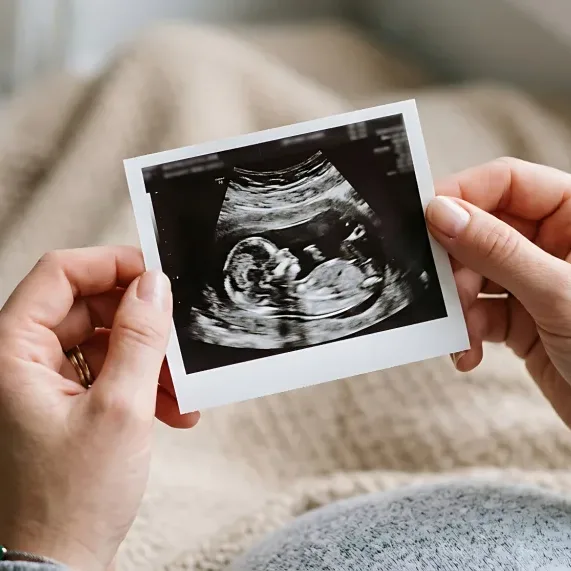 Hands holding ultrasound photo of fetus, representing pregnancy